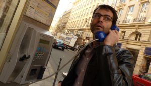 Un joueur écoute un indice dans une cabine téléphonique pendant un team building à Paris
